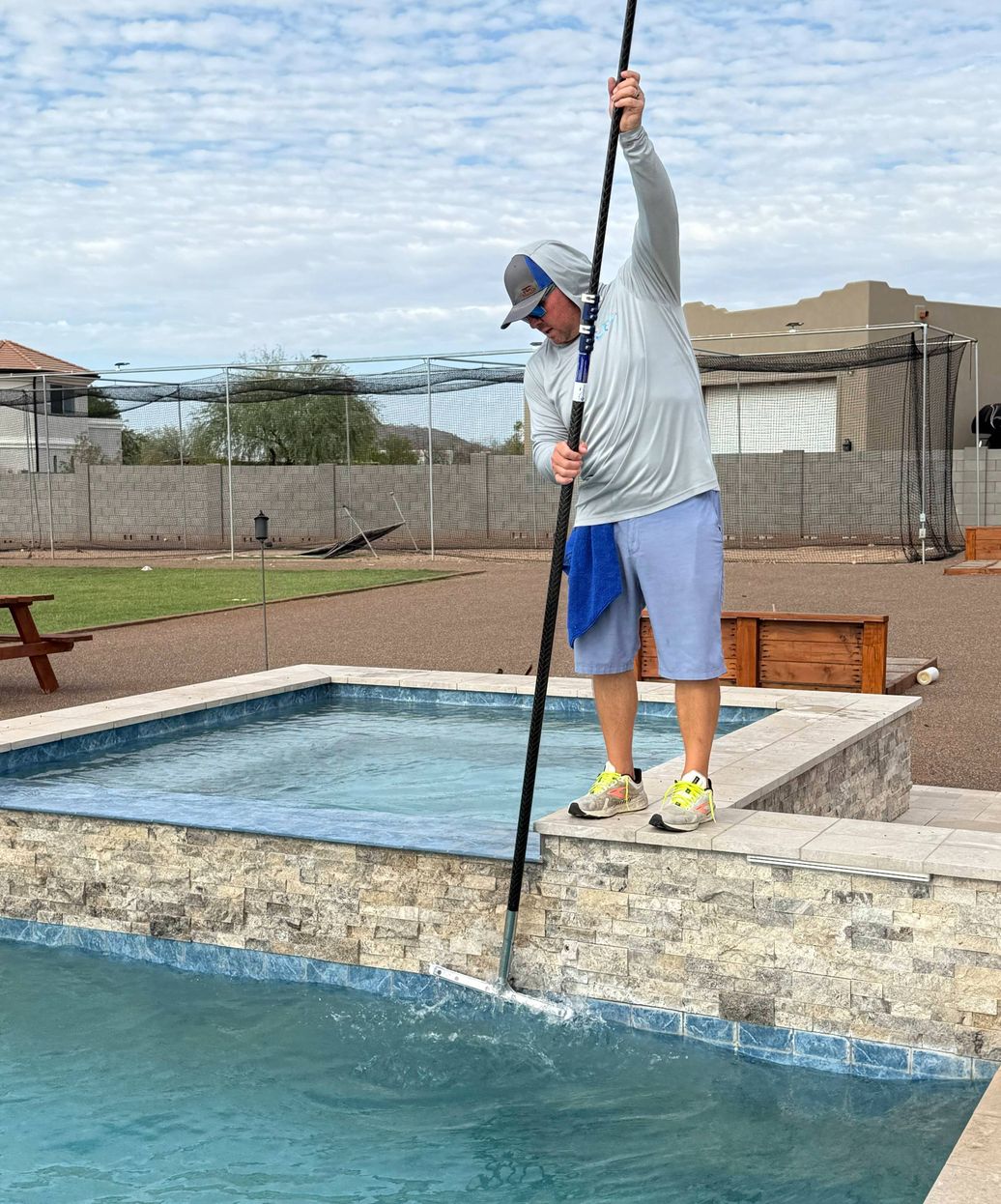 pool technician brushing and skimming pool surfaces